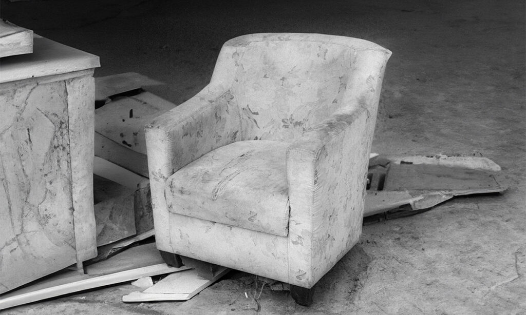 dumped couch and boxes left beside bins in an apartment building bin room